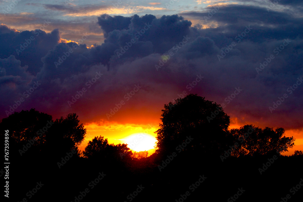 Dramatic clouds at sunset on the meadow nearby the lake Dramatic clouds at sunset on the meadow nearby the lake