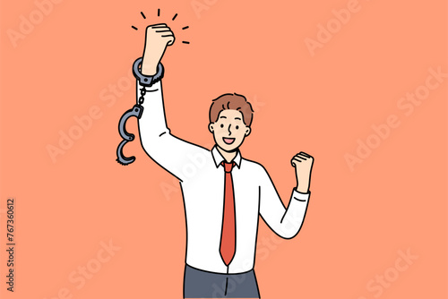 Business man feels joy after being fired from job with bonded working conditions, joyfully waving handcuffed hands. Successful guy celebrates being fired from unloved company with bad bosses