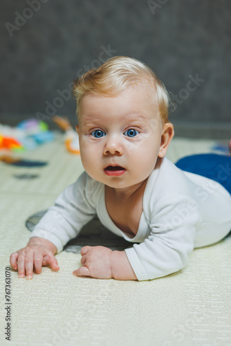 A 5-month-old baby is smiling and lying on a developmental mat. Self-development of the child.
