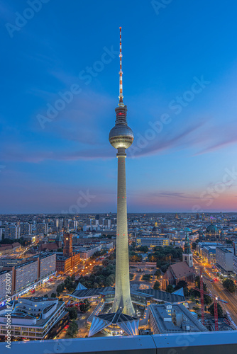 Television tower in the capital of Germany. View from the high-rise on Alexanderplatz in the center of Berlin. City landmark in the evening at blue hour. Illuminated street and high-rise buildings