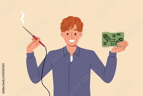 Man engineer with electronic circuit and power tool in hands rejoices at invention of new PCB for powerful computer. Designer guy invented electronic circuit smiles and looks at camera