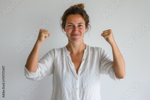 femme en chemise et veste levant les bras en l'air avec les poings fermés, heureuse et souriante, célébrant une victoire