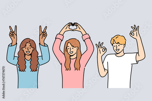 Multiethnic people students smiling showing approval gestures and raising hands up. Happy guy and two students girls rejoice at having multiracial friends and lack of discrimination in society