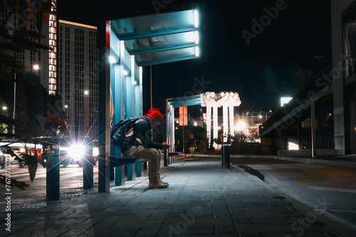 Persona esperando en la parada del transporte por la noche