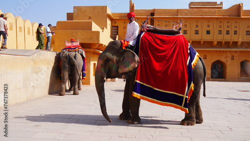 Balade à dos d'éléphant d'asie dans le fort Amber, promenade animalière incourtounable, plaisir touristique, voie royale, belle façade de bâtiment en brique ou pierre jaune ou orange, environnement  photo