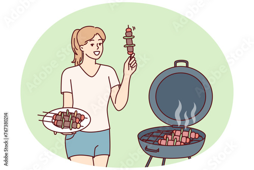 Woman barbecues on outdoor grill in backyard of home preparing for picnic party. Girl fries barbecues meat and BBQ vegetables on hot coals, wanting to get delicious snack with smell of smoke