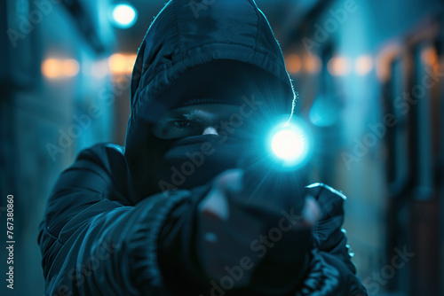 Thief in mask and clothes with flashlight on dark background