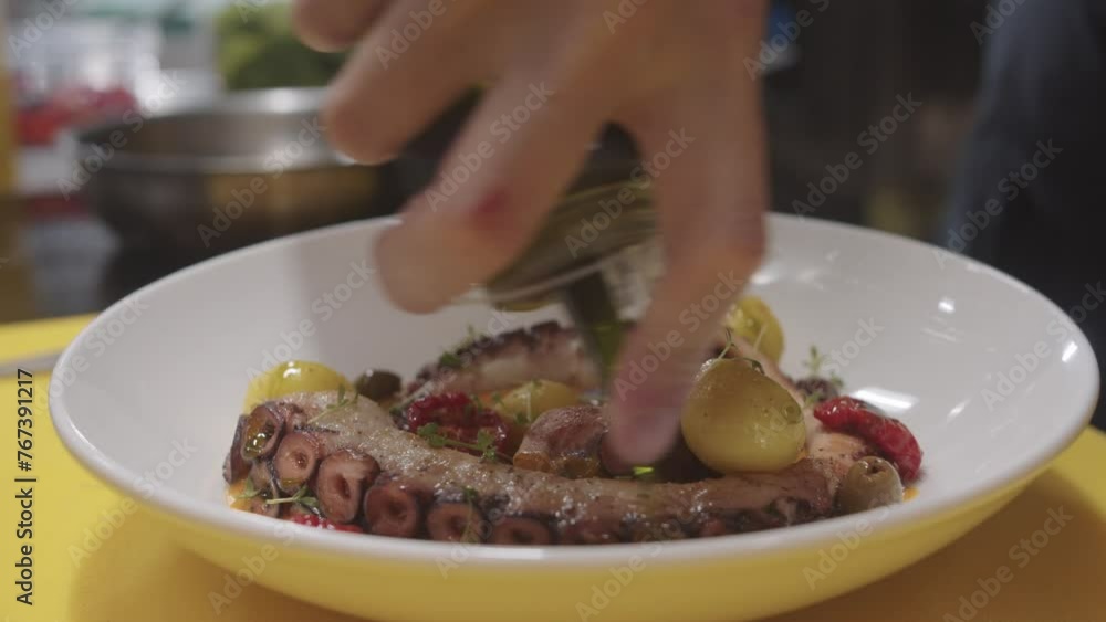 Chef add source into plate with seafood - octopus Chef add source into plate with seafood - octopus