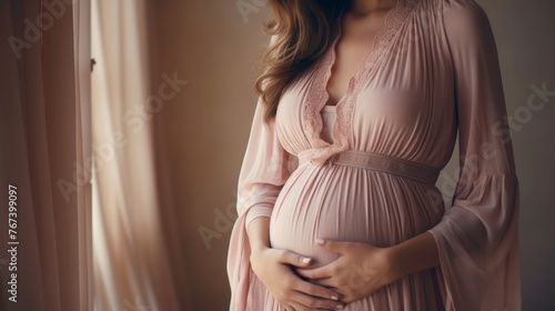 Elegant pregnant woman in pink dress with pregnancy belly - maternity background