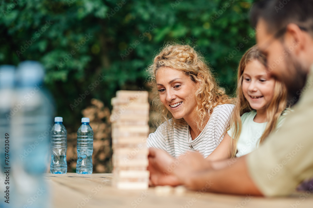 Cheerful family playing jenga game in nature. Cheerful family playing jenga game in nature.