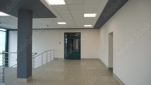 An empty spacious room of a modern office building with large windows. An empty hall with columns and a new renovation. Interior design. Suspended ceiling and square LED lamps.