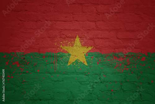 colorful painted big national flag of burkina faso on a massive brick wall