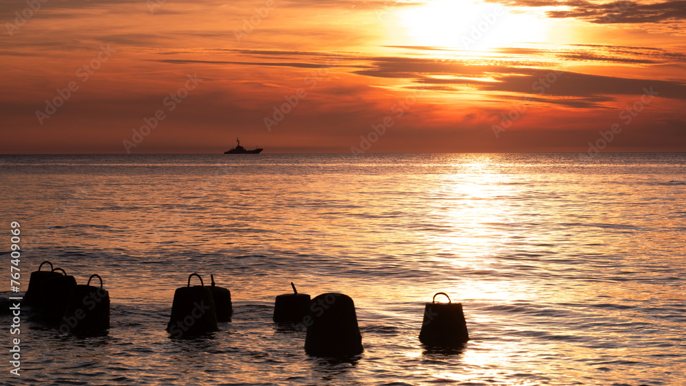 Statek wojskowy na morzu na tle zachodzącego słońca - obrazy, fototapety, plakaty 