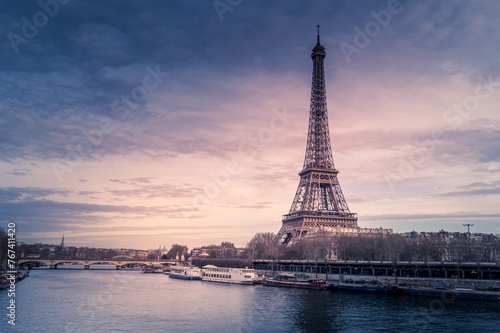 Beautiful wide shot of Eiffel Tower in Paris surrounded by water with ships under the colorful sky