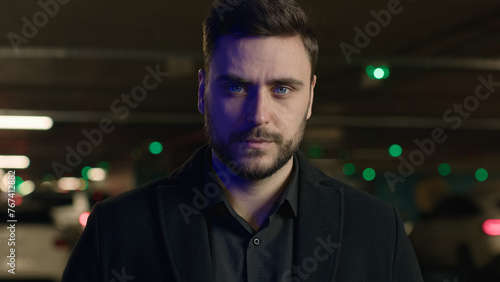 Portrait confident adult businessman business person millennial 30s man looking at camera serious face expression male driver professional employer entrepreneur in dark underground car parking outdoor © Yuliia