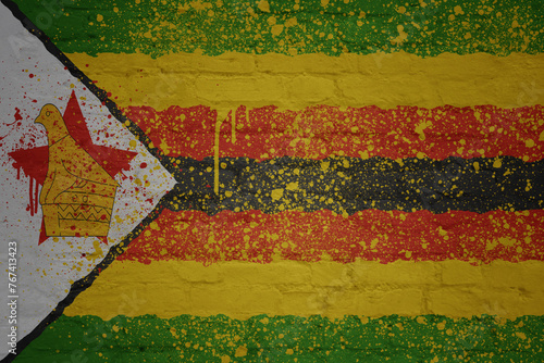 colorful painted big national flag of zimbabwe on a massive brick wall