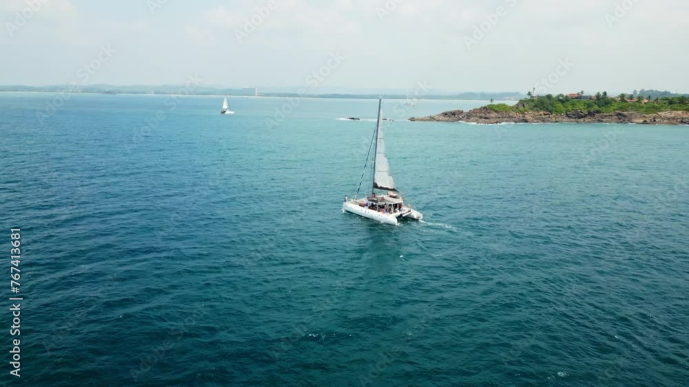 2023-03-15 - Mirissa Bay, Sri Lanka. Catamaran sails turquoise waters near coast, crew enjoys leisure sail. Aerial view captures holiday adventure, marine lifestyle. 2023-03-15 - Mirissa Bay, Sri Lanka. Catamaran sails turquoise waters near coast, crew enjoys leisure sail. Aerial view captures holiday adventure, marine lifestyle.