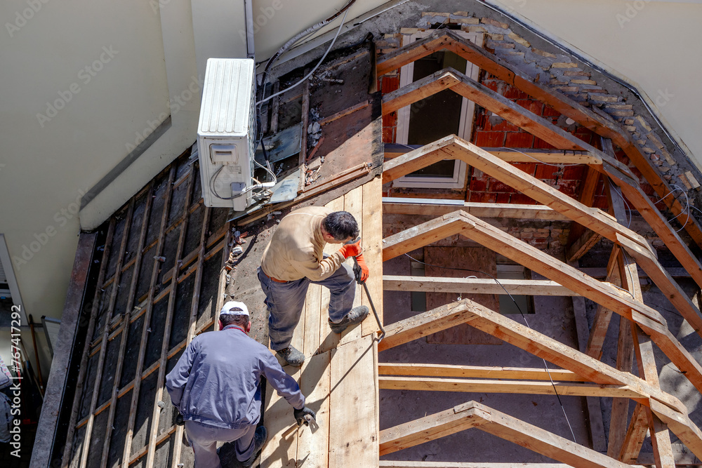 Construction workers remove the wooden structure when replacing the roof on the building. Roofer removing roof nails with roof shingle remover.