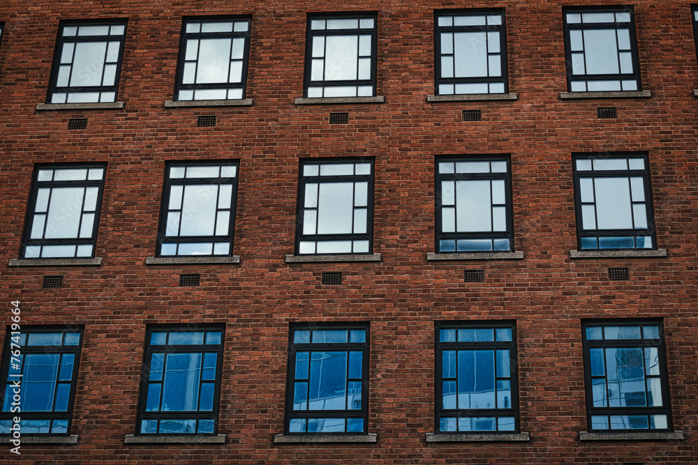 Facade of a brick building with symmetrical windows reflecting the sky in Leeds, UK. Facade of a brick building with symmetrical windows reflecting the sky in Leeds, UK.