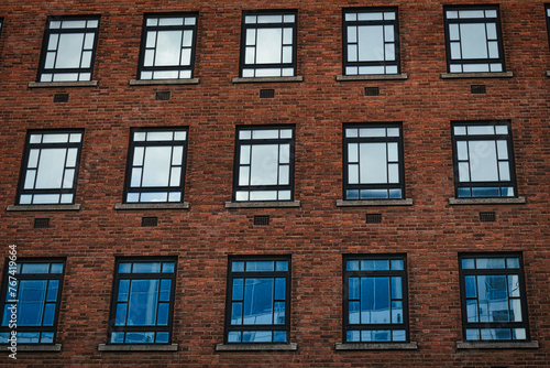 Facade of a brick building with symmetrical windows reflecting the sky in Leeds, UK.