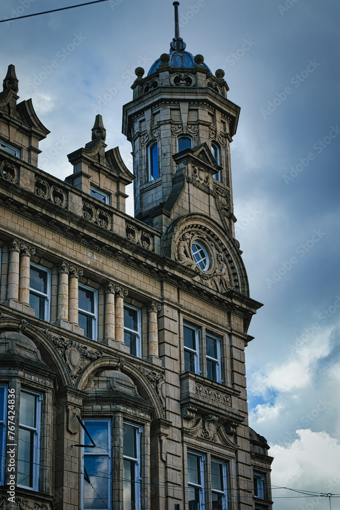 Vintage clock tower on an old European-style building against a cloudy sky in Leeds, UK.