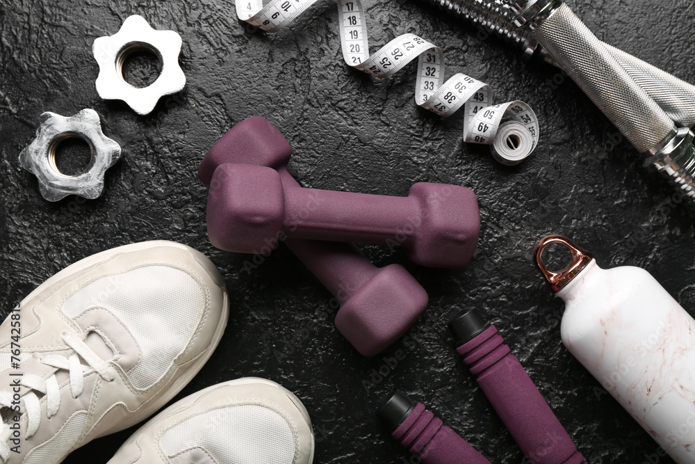 Dumbbells, shoes and measuring tape and clamps on black background - obrazy, fototapety, plakaty 