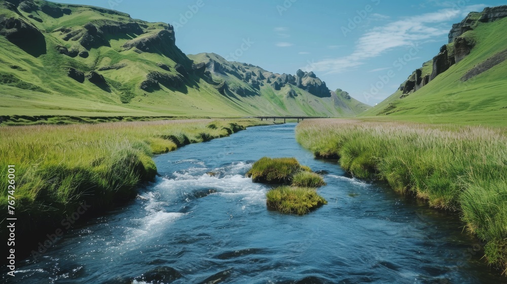  a river running through a lush green valley next to a lush green grass covered mountain covered with a blue sky.