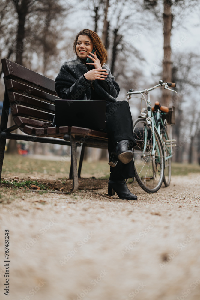 Attractive and confident young woman in stylish outfit enjoys a moment of relaxation on a park bench while using her phone. Attractive and confident young woman in stylish outfit enjoys a moment of relaxation on a park bench while using her phone.