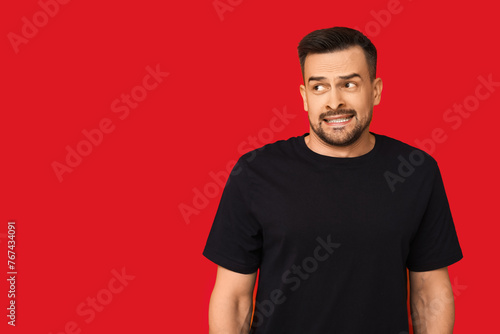 Photos Handsome ashamed young man on red background