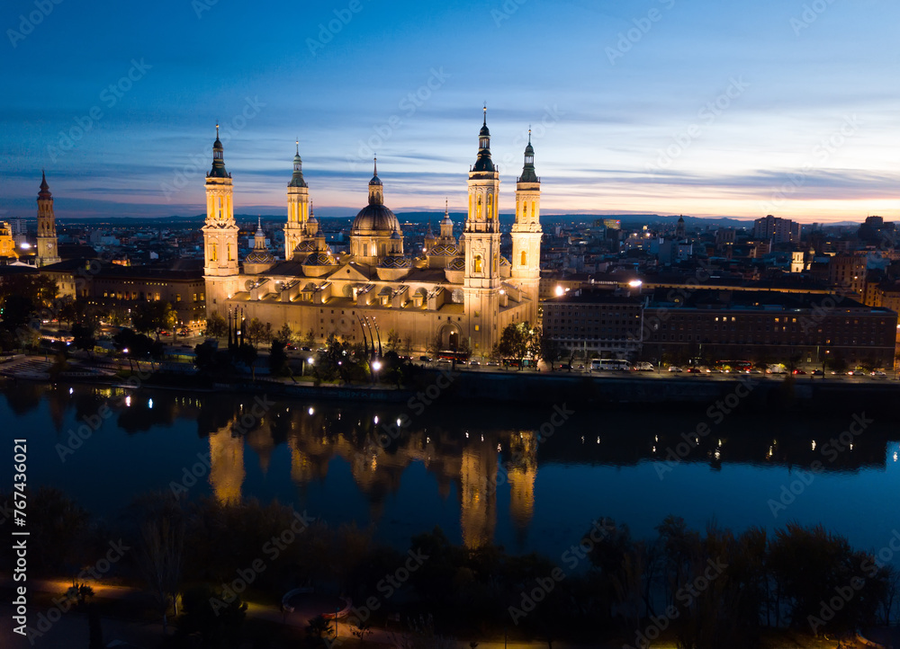 Scenic twilight view from drone of illuminated Basilica of Our Lady of Pillar on bank of Ebro river in Spanish city of Zaragoza ..