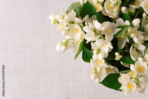 Bouquet of fresh delicate spring jasmine flowers on a linen tablecloth on the table. Top view  empty space. 