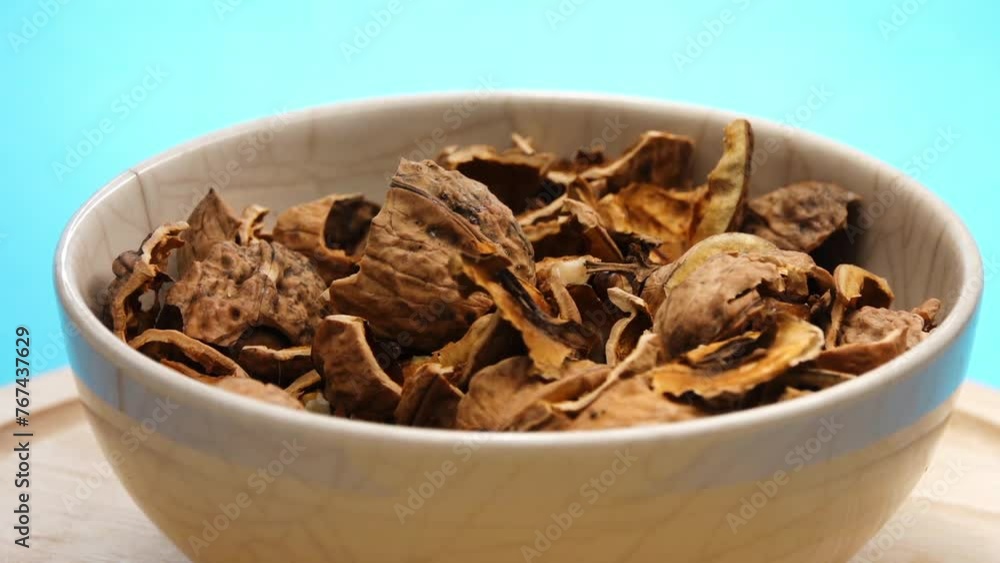 The shells from the buckwheat nuts rotate in a large bowl on the table. Green background. The shells from the buckwheat nuts rotate in a large bowl on the table. Green background.
