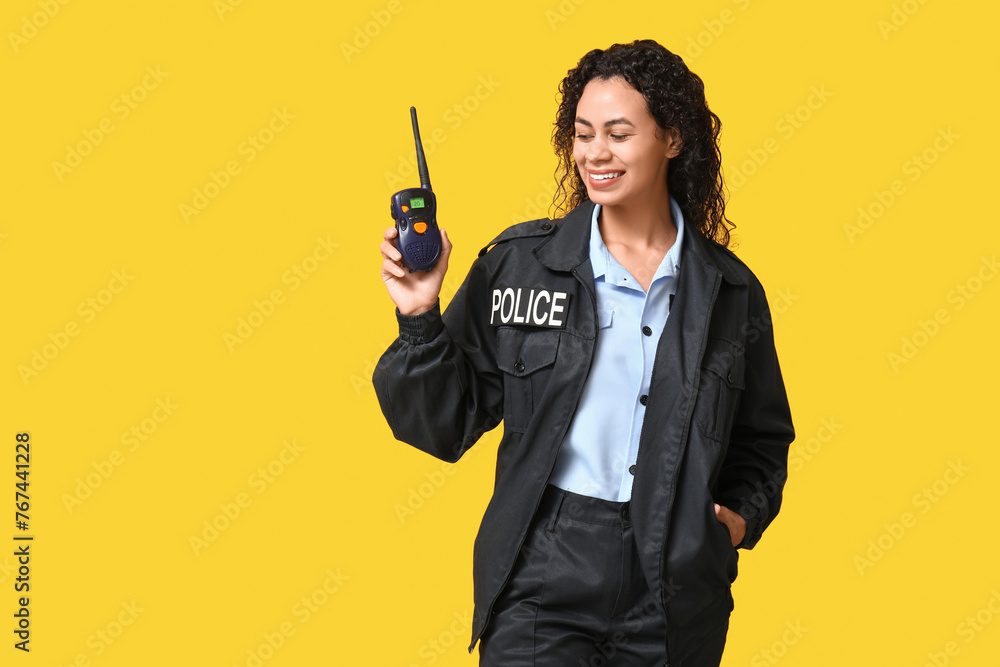 Beautiful young happy African-American policewoman with radio transmitter on yellow background Beautiful young happy African-American policewoman with radio transmitter on yellow background