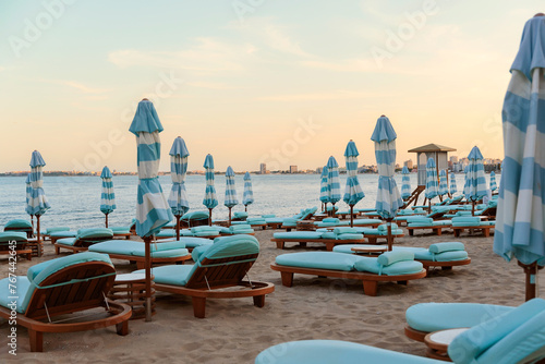 Empty sunbeds and umbrellas on a sandy beach near the sea