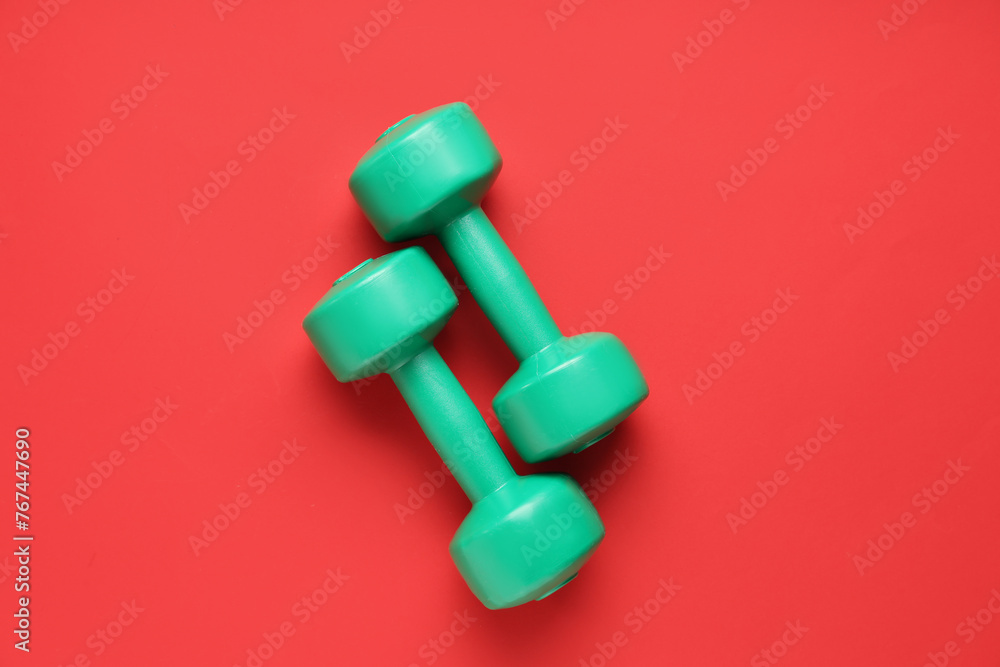 Pair of green dumbbells on red background Pair of green dumbbells on red background