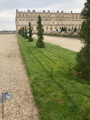 Gardens of Versaille with Orangerie meticulously manicured lawns precise geometric patterns bordered by vibrant flower beds bursting with colour 