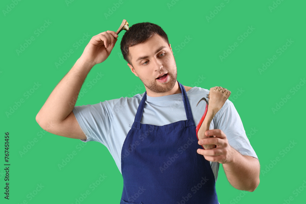 Thoughtful male shoemaker with broken heel on green background Thoughtful male shoemaker with broken heel on green background