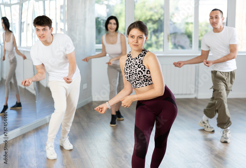 Group of happy young people enjoying a contemporary dancing class. Team of smiling dancers in casual wear practising a new choreo
