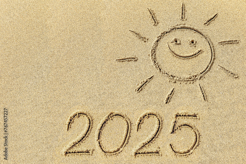  Drawing sun and 2025 on the sandy beach of the coastline as a symbol of the beach season