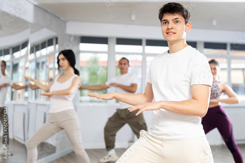 During dance workshop, guy enjoys active dancing, learns new movements, moves synchronously with participants of lesson. Concept of beautiful body through sports, dancing, and active lifestyle
