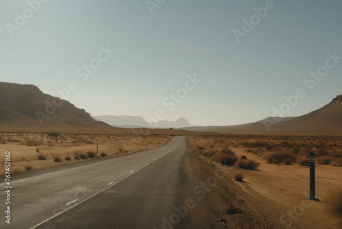 Empty desert road in the sand dunes and mountains. sun, heat and clouds of dust