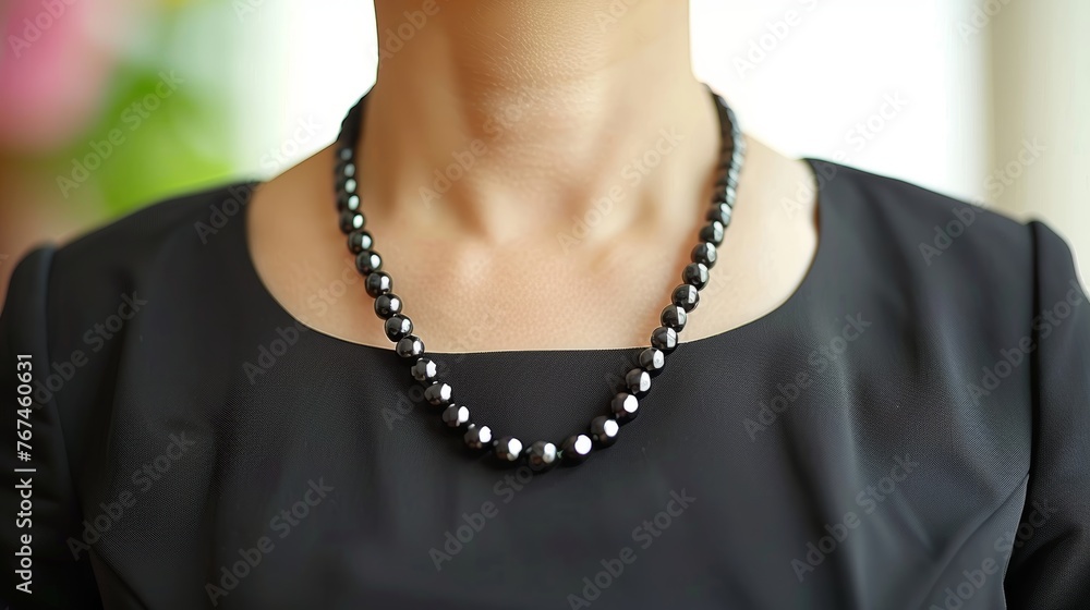 Elegant woman in black dress and necklace in studio setting with ample copy space for advertising