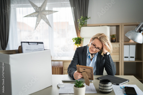 Mature woman lost her job fired from work pack personal items in box photo