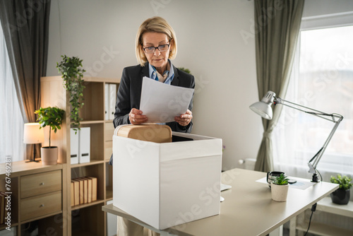 Mature woman lost her job fired from work pack personal items in box photo