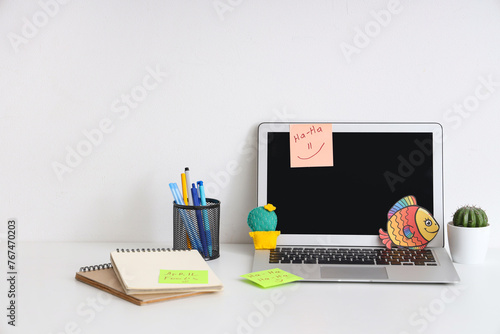 Workspace with laptop, funny sticky notes and paper fish on white background....
