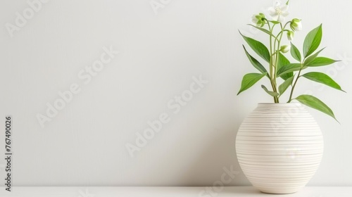  a white vase filled with a green plant on top of a white table with a white wall in the background.