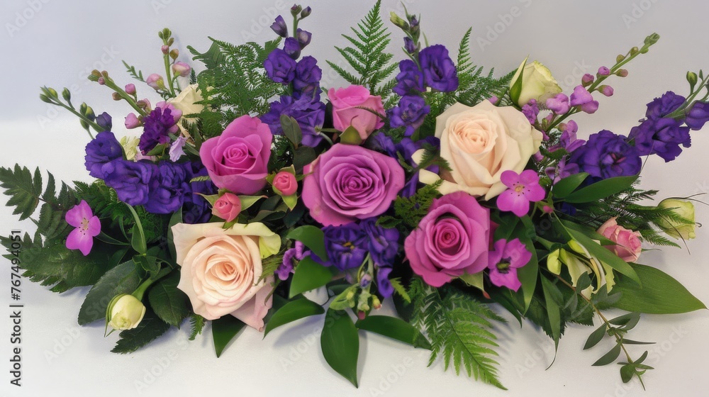 a close up of a bouquet of flowers on a white surface with purple and pink flowers in the center of the bouquet. a close up of a bouquet of flowers on a white surface with purple and pink flowers in the center of the bouquet.