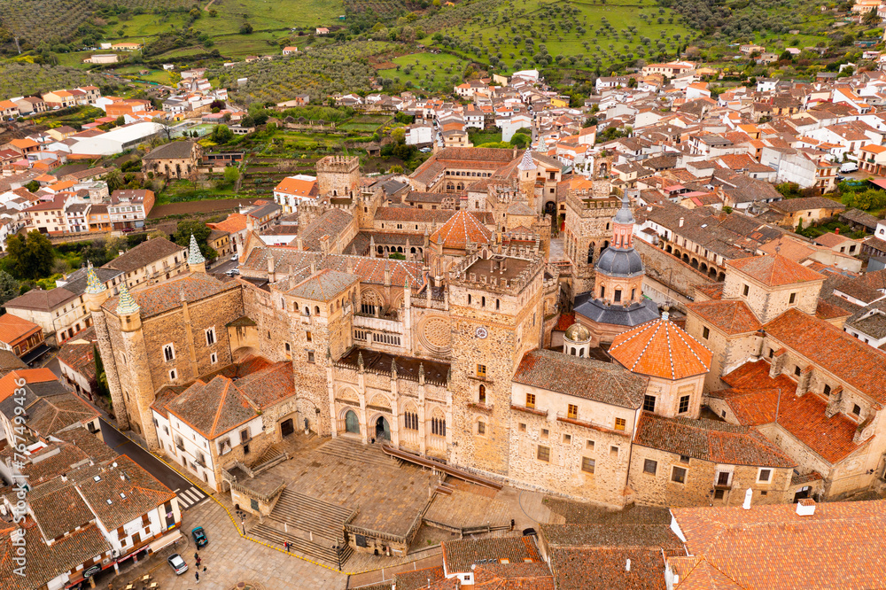 Aerial photo of residential buildings with tiled roofs in Guadalupe, Spain. Monastery of Saint Mary visible from above.