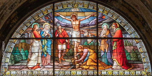 MILAN, ITALY - MARCH 4, 2024: The crucifixion in the stained glass in the church Basilica di Santo Stefano Maggiore by Costante Panigati (1898).