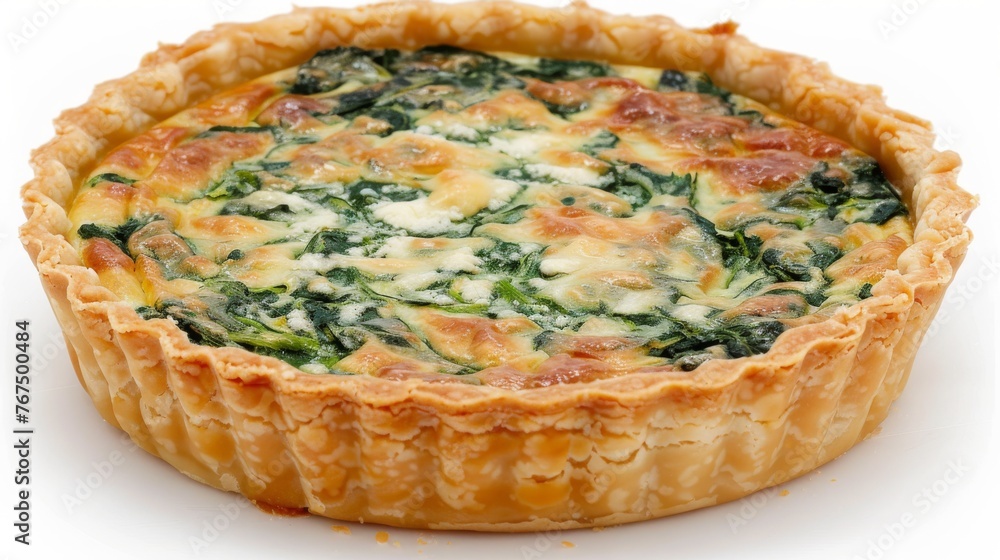 a quiche with spinach and cheese in a tart dish on a white surface with a white background. a quiche with spinach and cheese in a tart dish on a white surface with a white background.